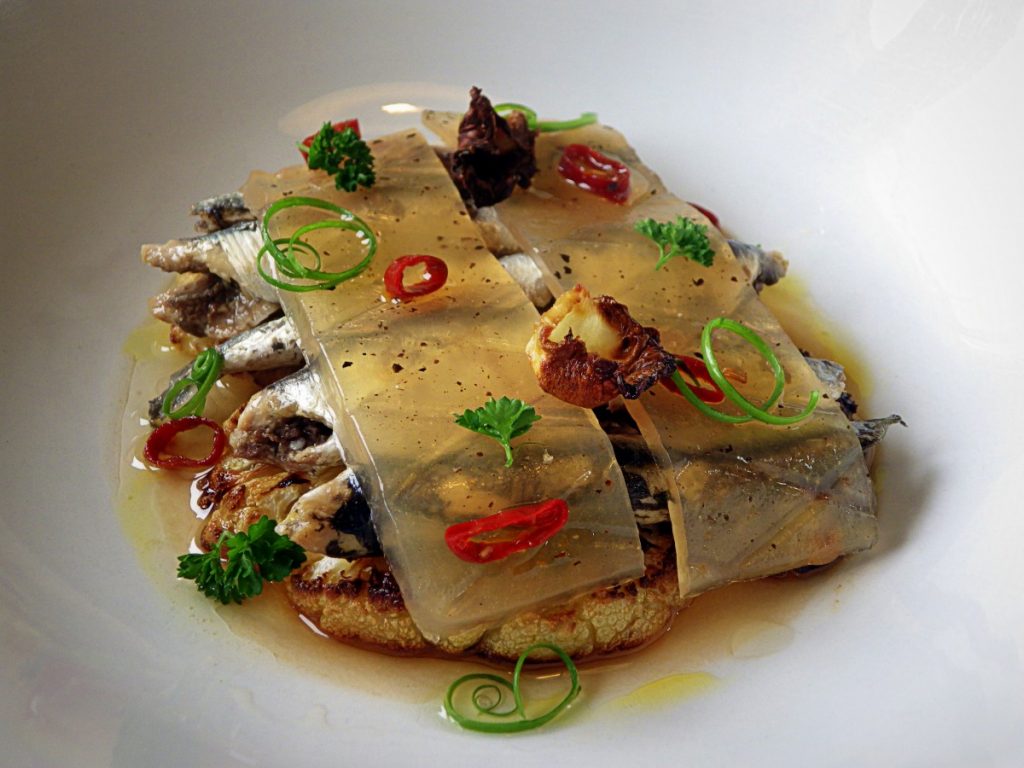 El mar condimentado en un plato con anchoas a la donostiarra Olasagasti, coliflor y gelatina de tomate